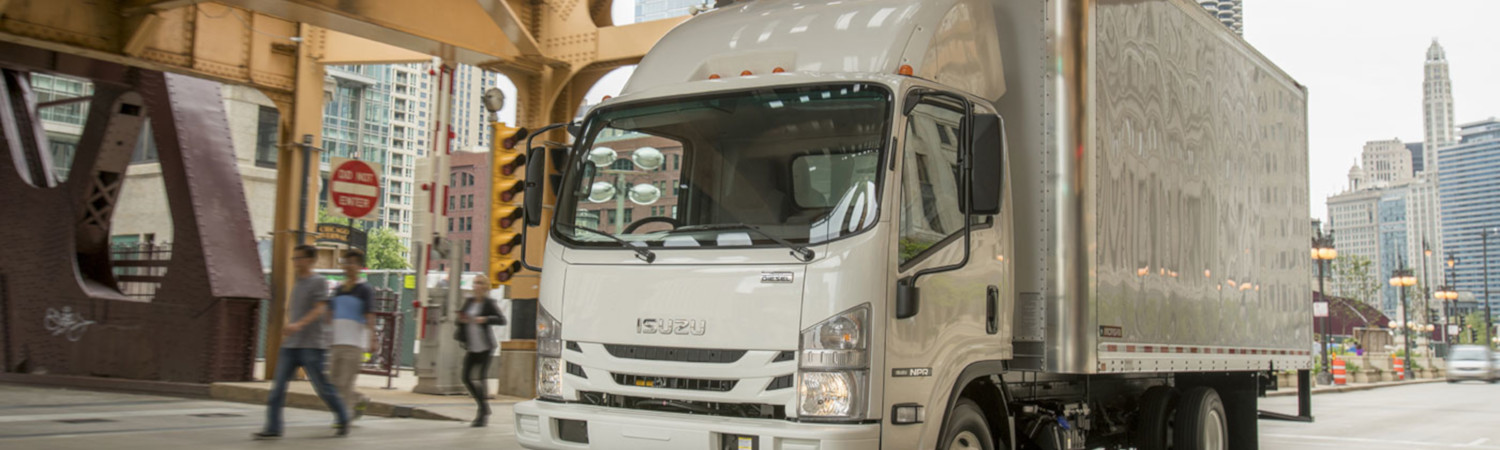 A 2020 Isuzu box Truck travels through a business city on it's delivery route. 