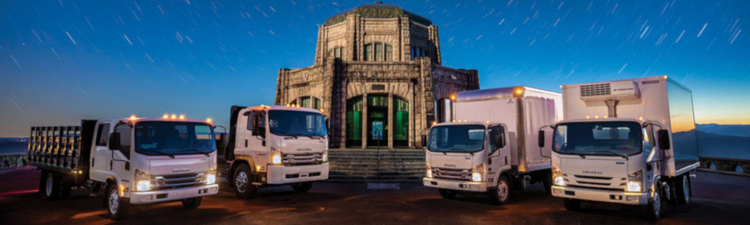 A lineup of 2020 Isuzu Trucks parked in front of a dome-like building.